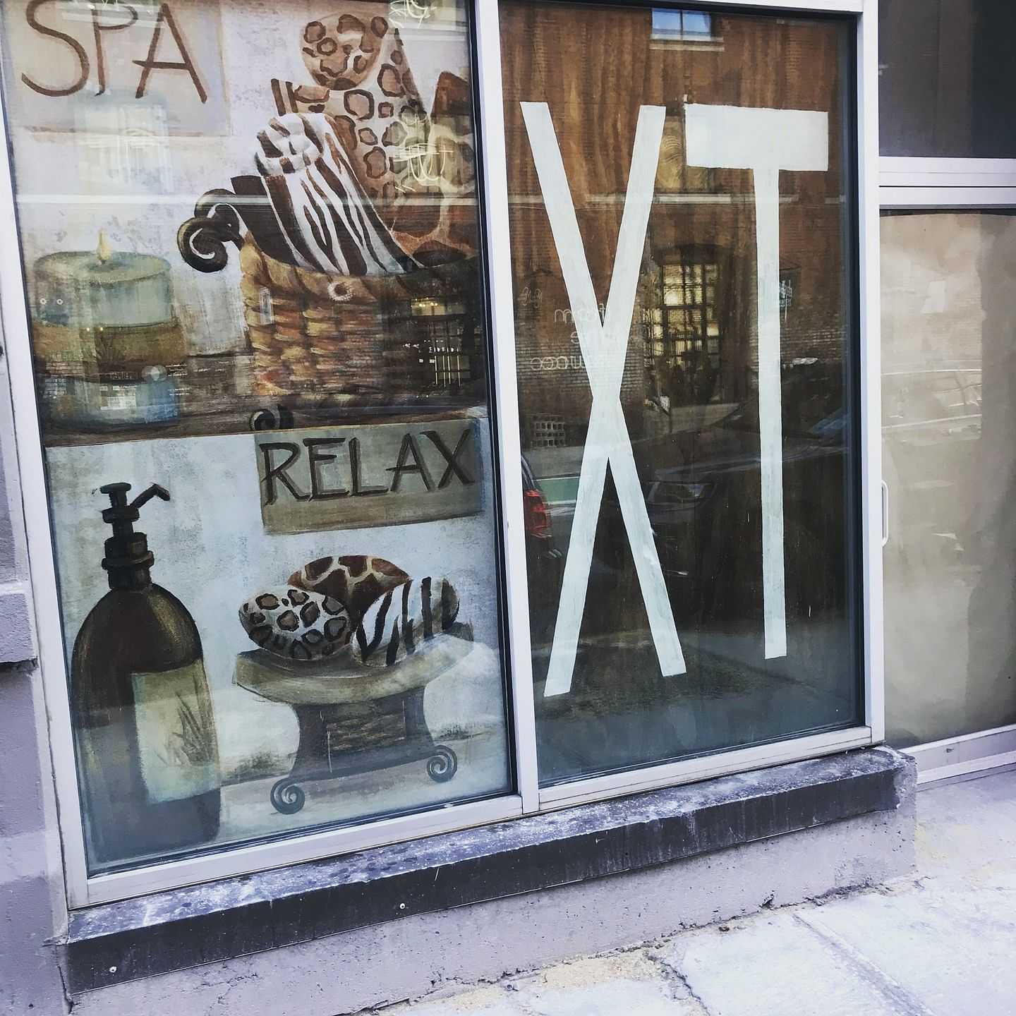 Storefront window displaying painted items including candles, a basket, and the text "RELAX XT".